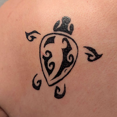 A sea turtle linework tattoo on a shoulder