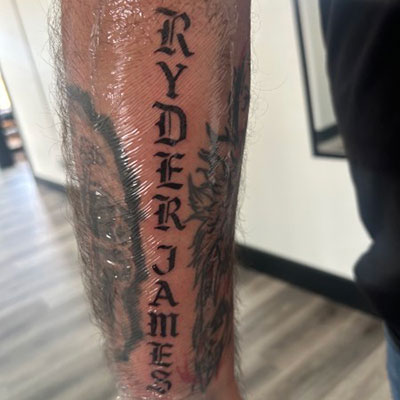 The name Ryder James tattooed on a forearm