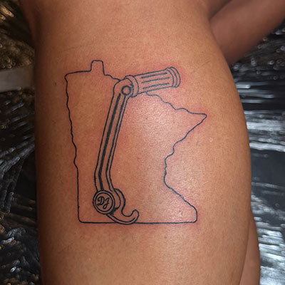 A tattoo of the state of Minnesota with a motorcycle kick starter.